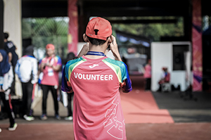 Young man wearing a volunteer shirt taking photographs