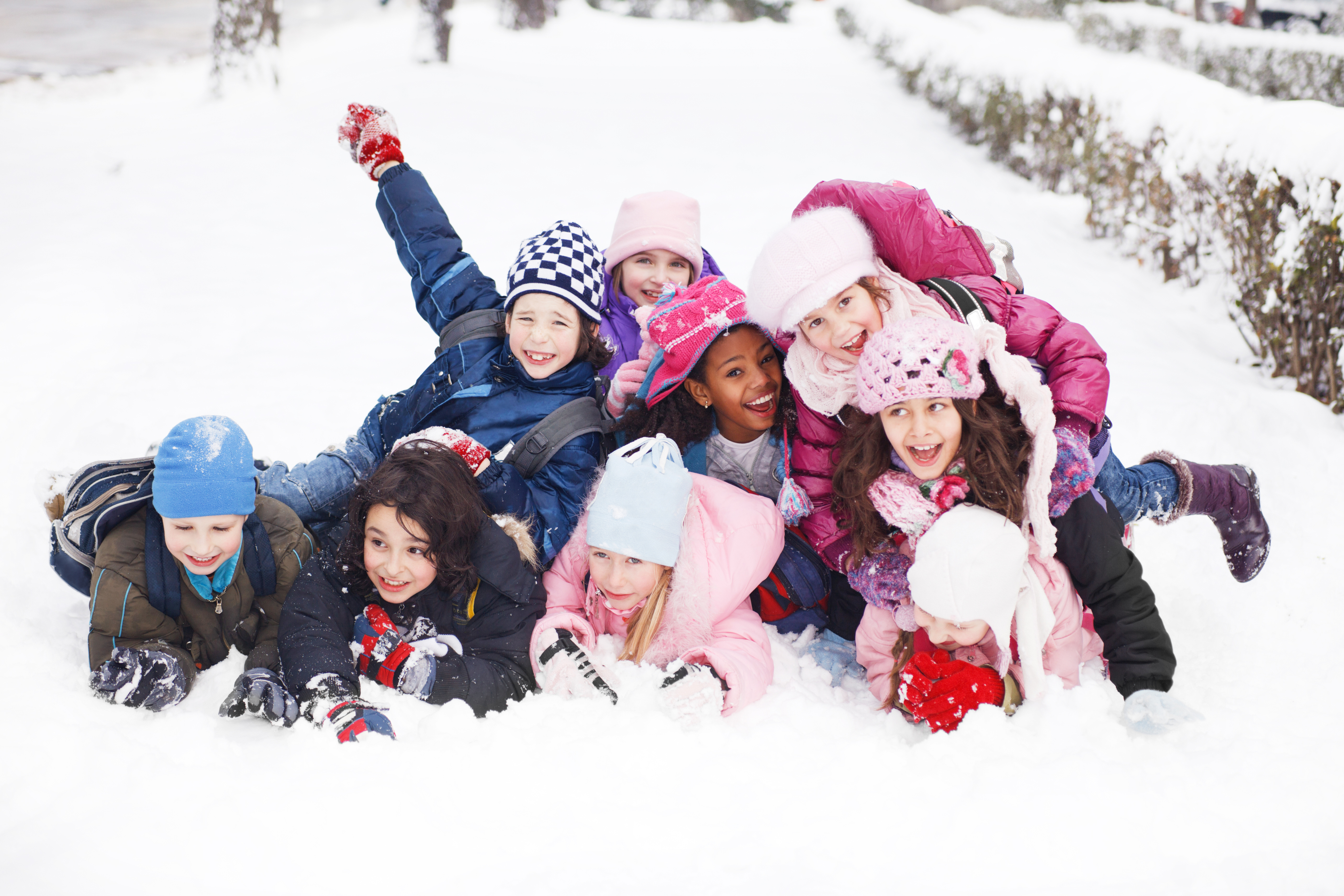 Un groupe d'élèves, tous vêtus d'habits de neige, de tuques et de gants en prévision du froid, s'amusent ensemble dans la neige. 