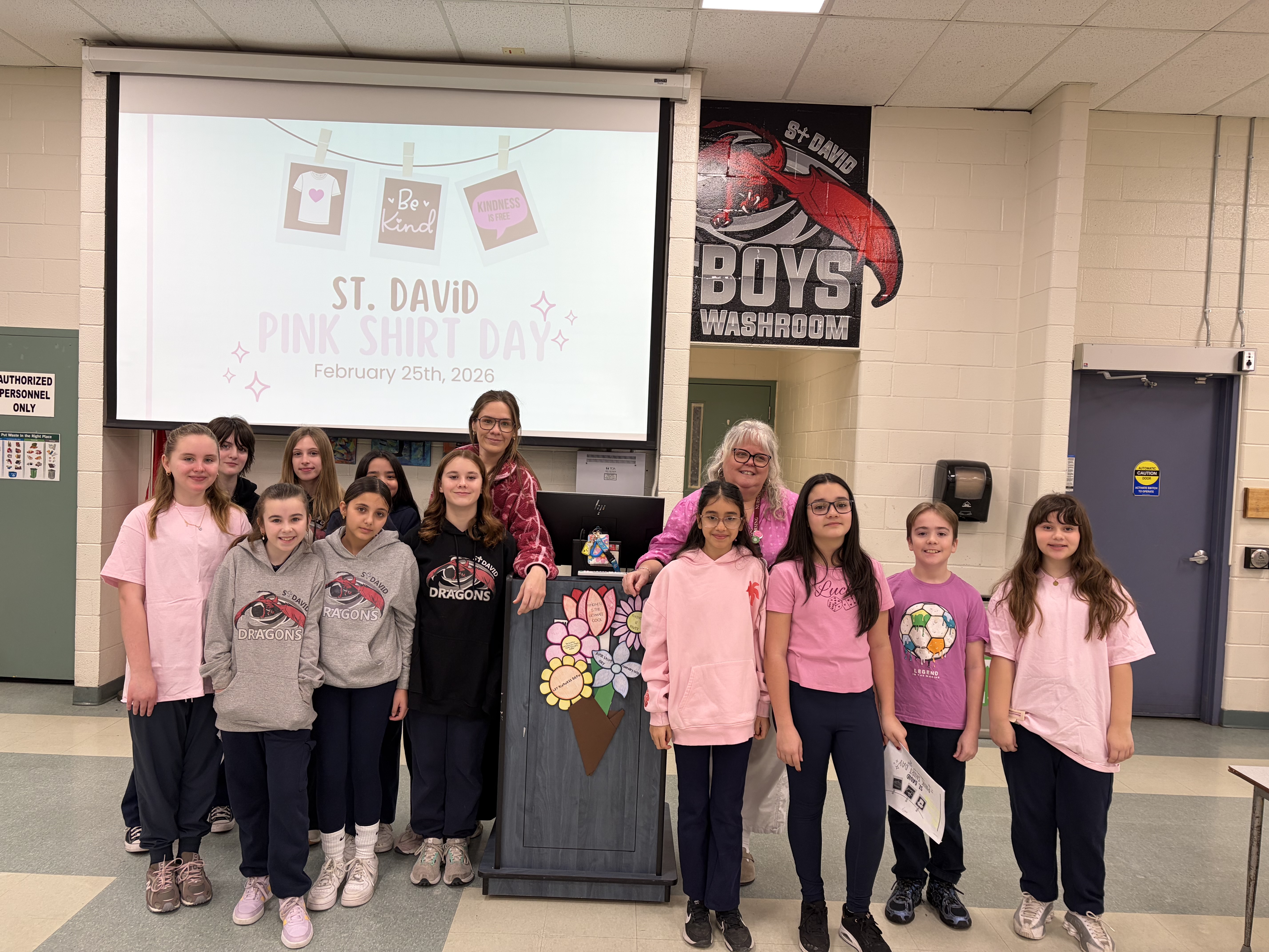 A group of students and educators wearing pink, smiling at the camera