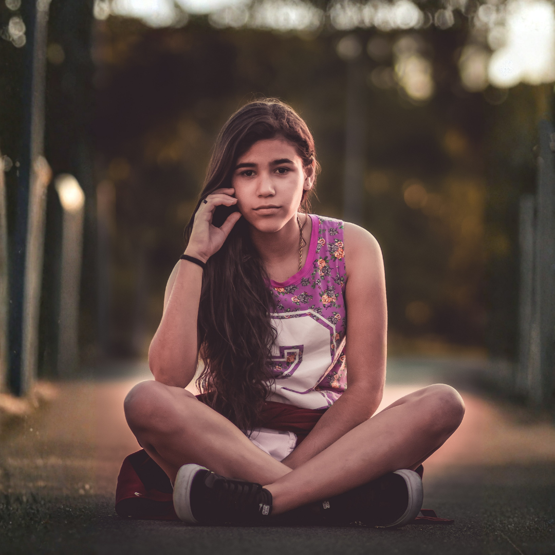 Une jeune fille est assise par terre, l'air pensif.